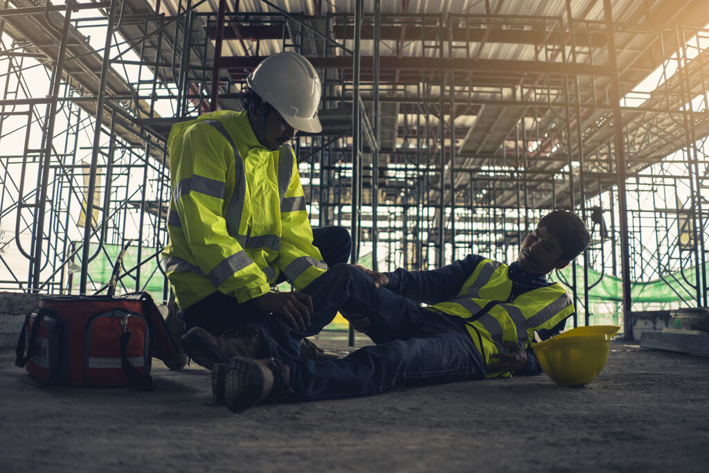 Construction worker laying on the ground of job site injured needing to speak to a construction accident lawyer.