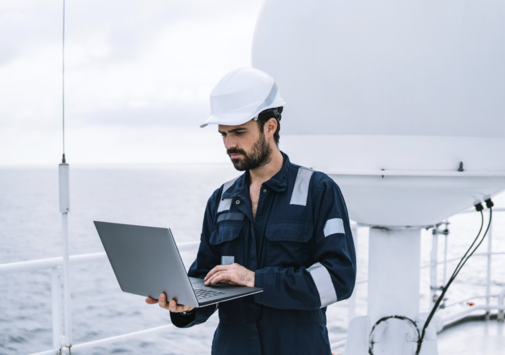 An offshore worker standing on a boat looking at computer. A Construction attorney can help if you’ve recently been injured offshore.