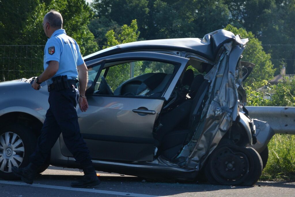 A police officer walking past a car totaled in a car wreck. In devastating crashes, injuries sustained can leave you unable to work for long periods of time. Our car accident lawyers in Houston can help.