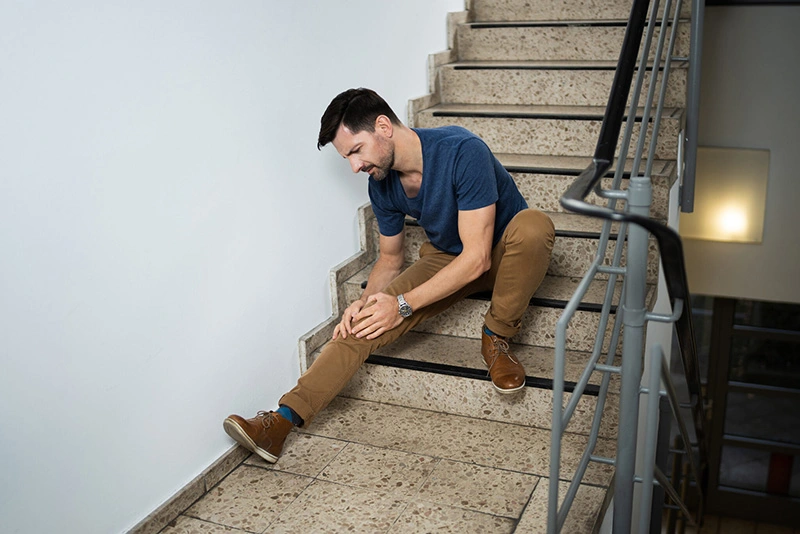 Man sitting on stairs after slip and fall accident. If you’ve been injured on someone’s property, our slip and fall lawyers can help you recover the damages you deserve. 