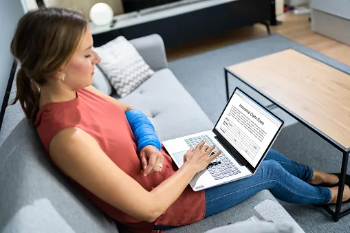 Woman sitting on couch with a cast looking for a personal injury lawyer on the internet.