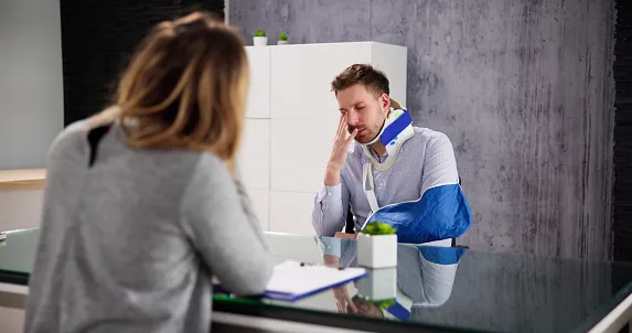 Man speaking with his personal injury lawyer after an injury to his arm where he has to wear a neck brace and sling. Employer Liability in Texas