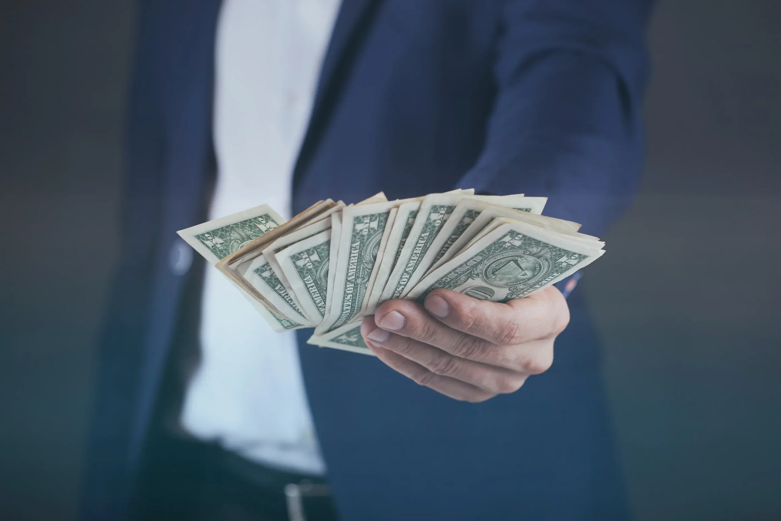 A person holding a stack of dollar bills.